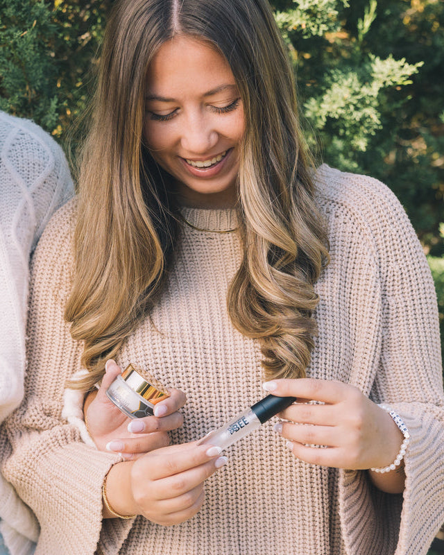 Woman holding a Generation Bee skincare product outdoors