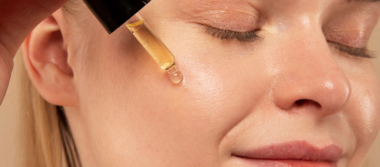 Woman applying a dropper of Generation Bee oil to her face.