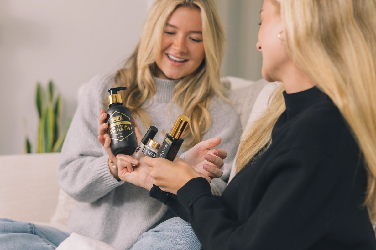 Two women sitting on a couch with skin care essentials